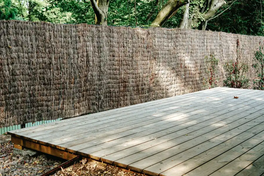 A finished wooden deck surrounded by mature green trees