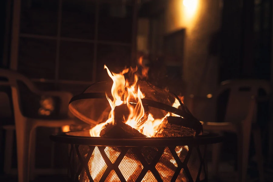 A finished fire pit with glowing flames set in a backyard patio