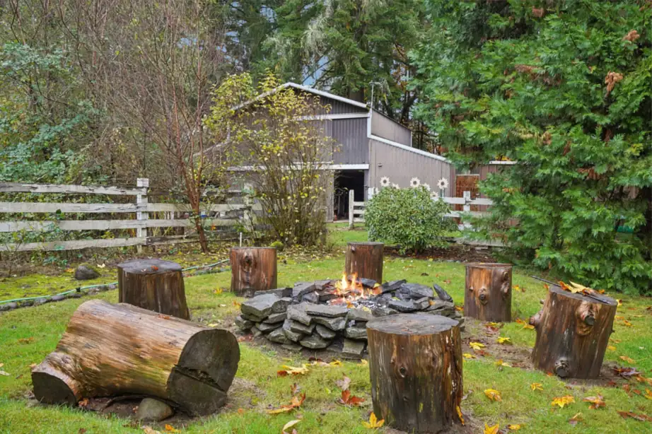 A backyard fire pit ringed with log seating in a quiet garden setting