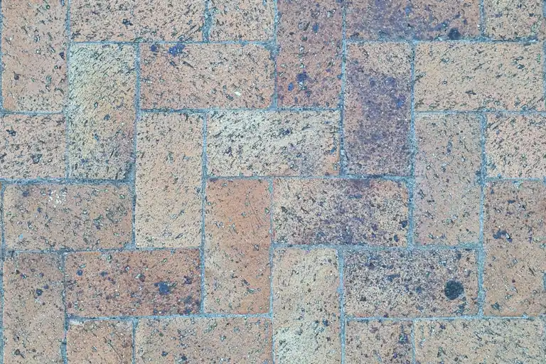 A herringbone pattern brick paver surface laid in a backyard