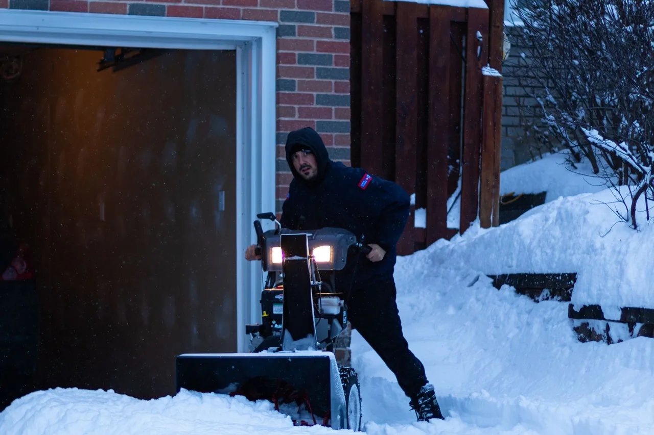 A snowblower clearing deep snow from a residential driveway